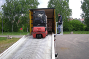 Die Be- und Entladung von Rollen von LKWs erfolgt mit einer mobilen Laderampe. An der Laderampe wurde seitlich ein Podest montiert, welches den LKW-Fahrern einen festen Stand außerhalb des Gefahrbereichs ermöglicht.