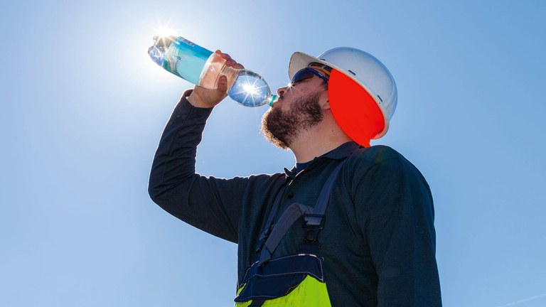 Arbeiter im Freien trinkt Wasser und ist durch Kleidung und Schutz vor der Sonne geschützt. 